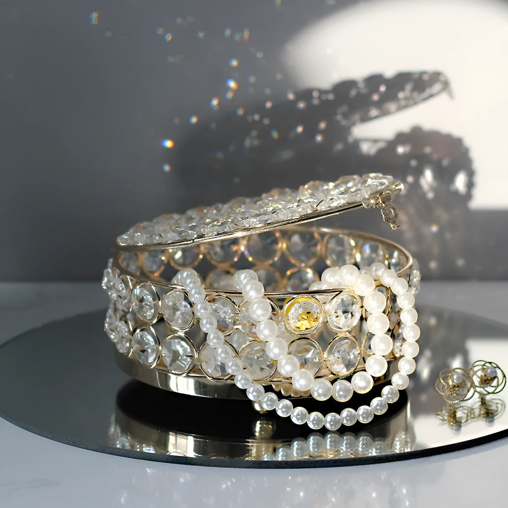 Crystal clear glass jewelry box with French gold metal frame on a table.