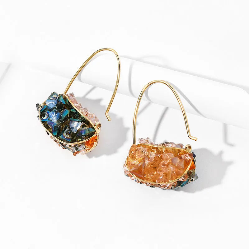 Pair of champagne gold geometric quadrilateral drop earrings on a neutral background