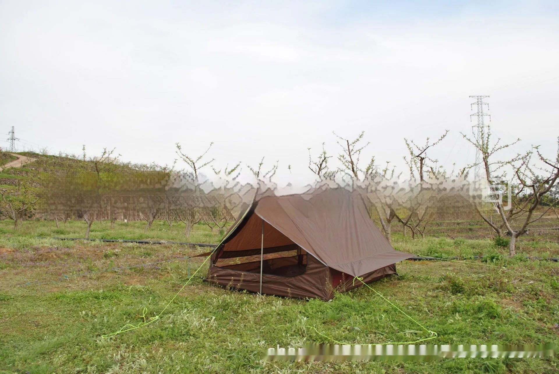 Brown A-line hiking tent pitched using trekking poles with guy ropes secured