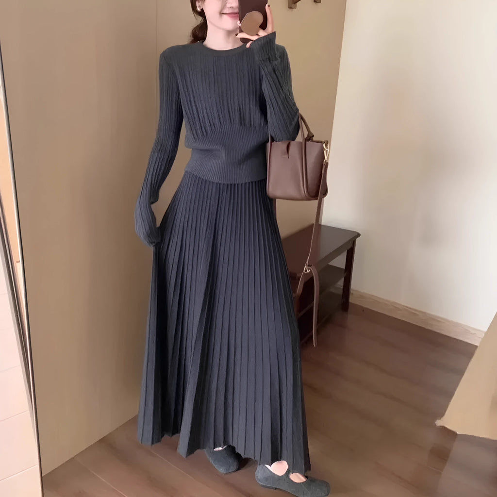 Dark grey knitted women's sweater and skirt set with a raised 3D pattern, laid flat.