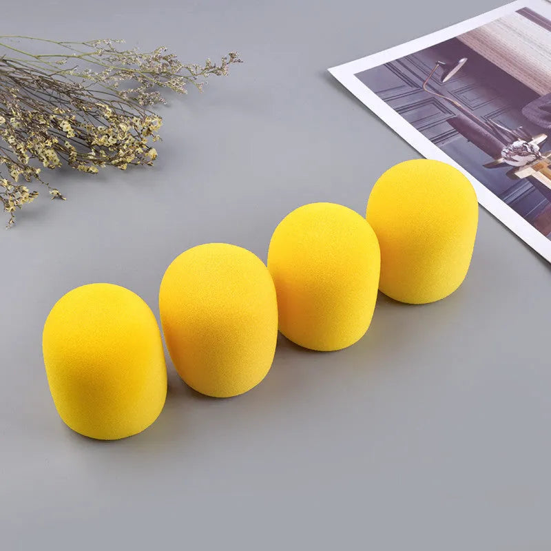Four multicolored foam microphone windshields for handheld stage microphones on a grey background.