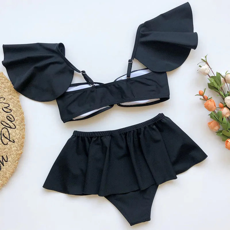 Women's black three-piece flounced bikini swimsuit with ruffled details on mannequin