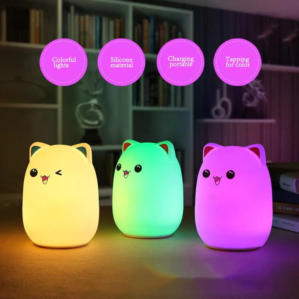 Cartoon silicone clapping night lamp in pink with USB charging cable on a bedside table