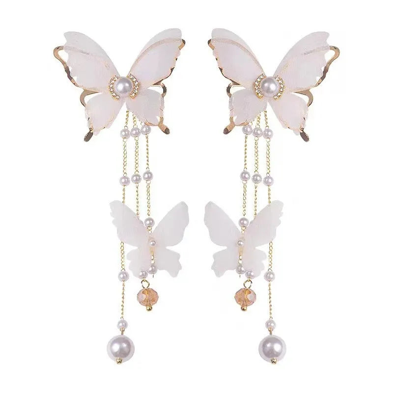 White butterfly-shaped drop earrings with rhinestones, a long chain tassel, and a pearl tip on a white background.
