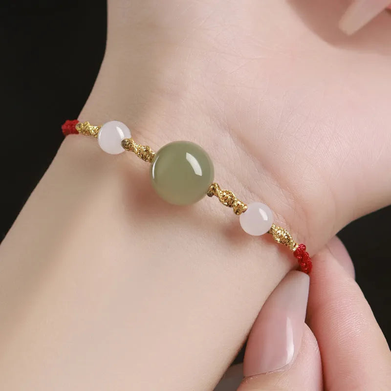 Hand-woven wine red rope bracelet with Hetian jade lucky beads and ethnic symbols.