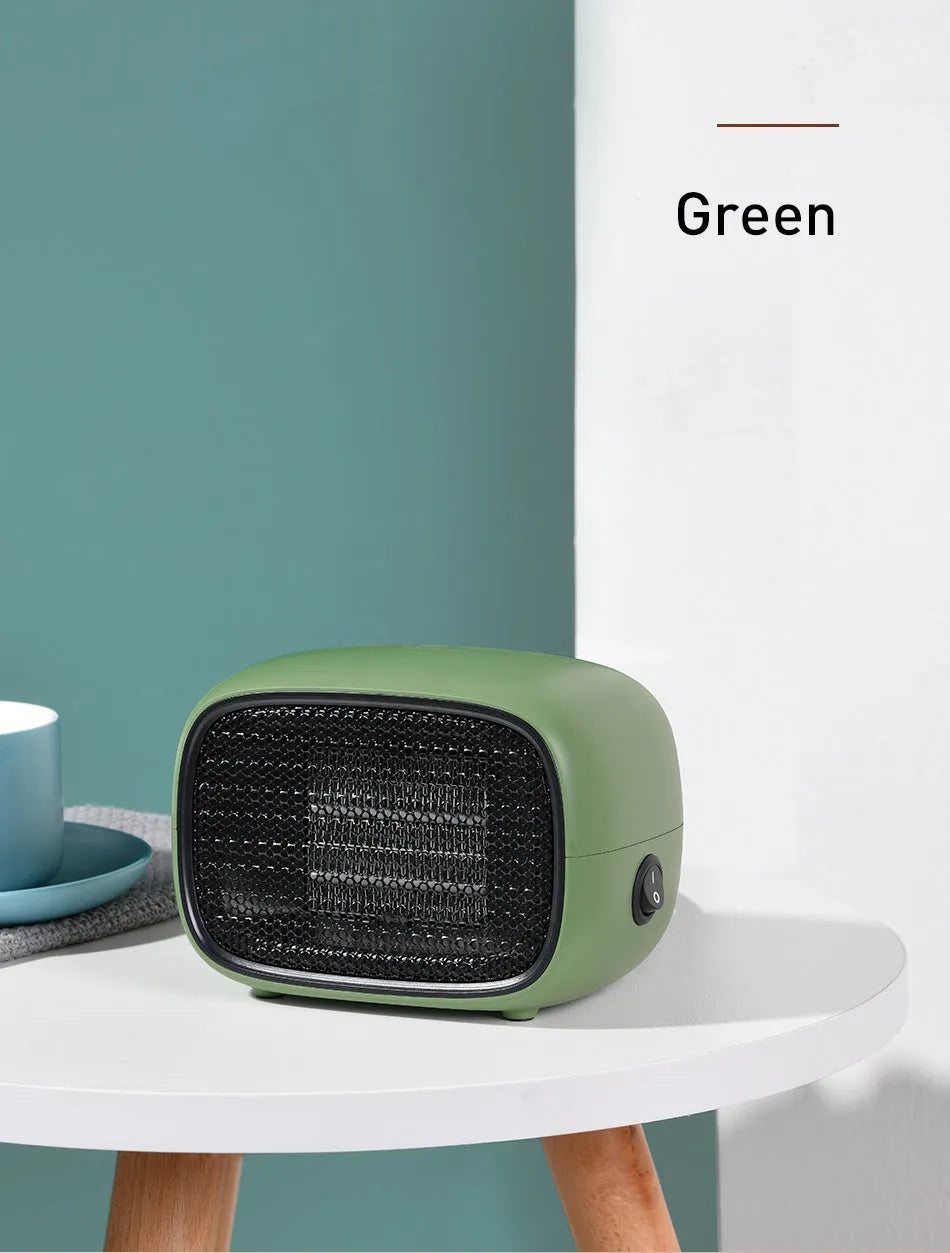 Compact green mini desktop heater with metal grille and EU plug on a wooden desk.