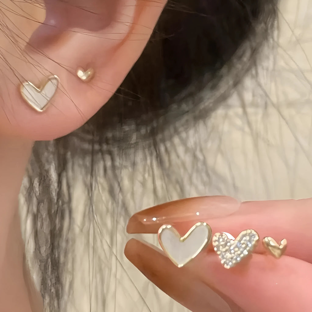 Three pairs of heart-shaped alloy earrings in gold, black, black and white, and pink colours