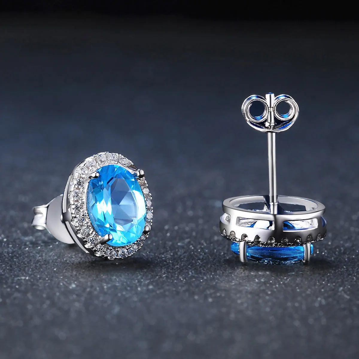 Women's four-piece sterling silver jewellery set with blue topaz gems, showing geometric earrings, ring, pendant and necklace.