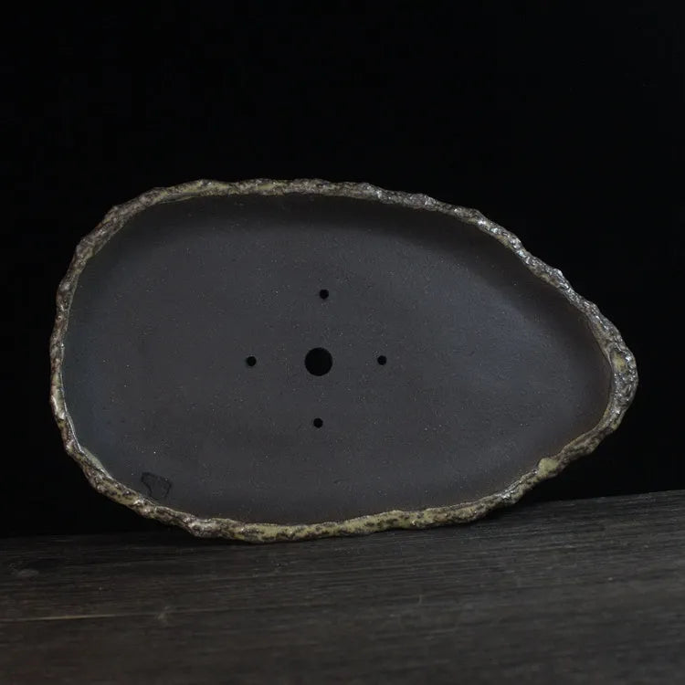 Handmade purple clay flower pot with drainage hole on a wooden floor