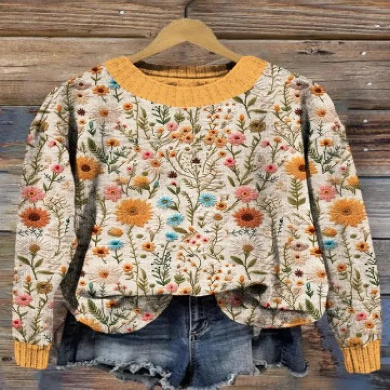 A round neck sweater with a colourful digital floral print, shown on a hanger.