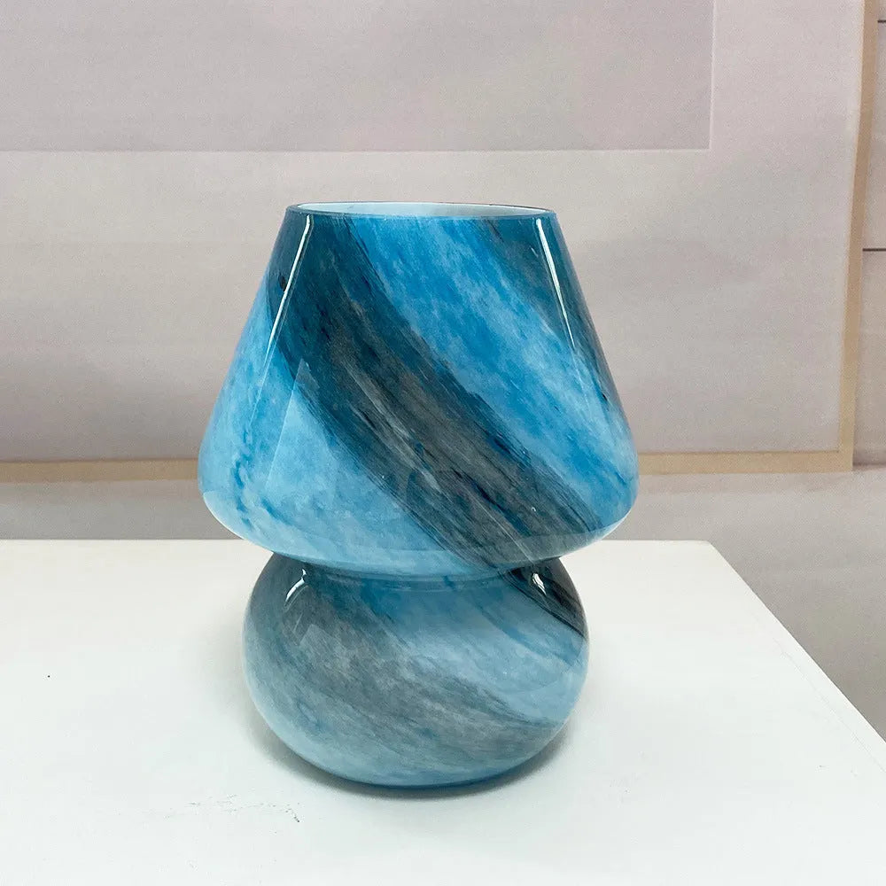 Handmade glass mushroom table lamp in Earth colour on a wooden bedside table with a soft glow