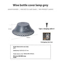 Beige recycled wine bottle camping lantern with USB-C port, showing warm light glow.