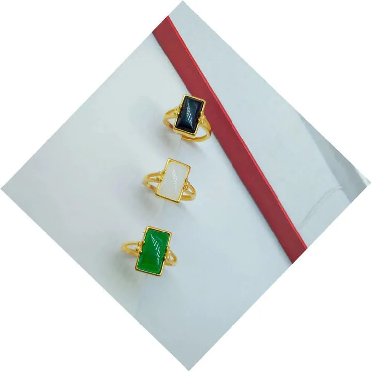 Adjustable brass gold-plated ring with a coloured gemstone inlay on a finger.