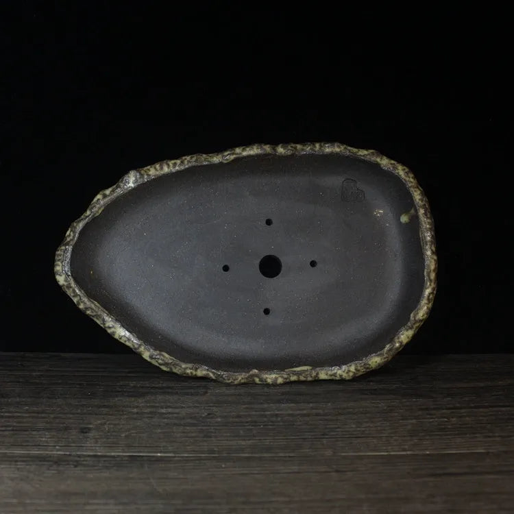 Handmade purple clay flower pot with drainage hole on a wooden floor