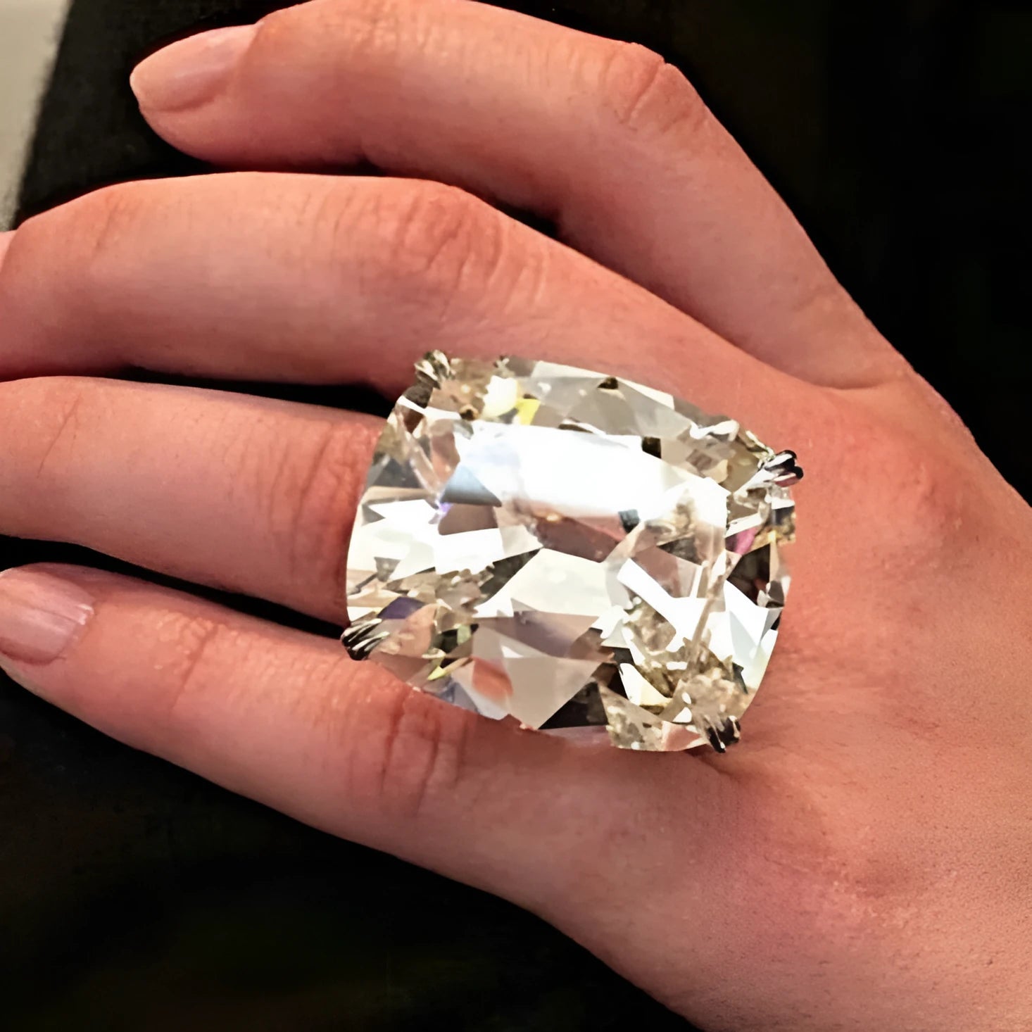 Simple women's alloy ring with an inlaid square diamond design in white gold colour on a model's finger.