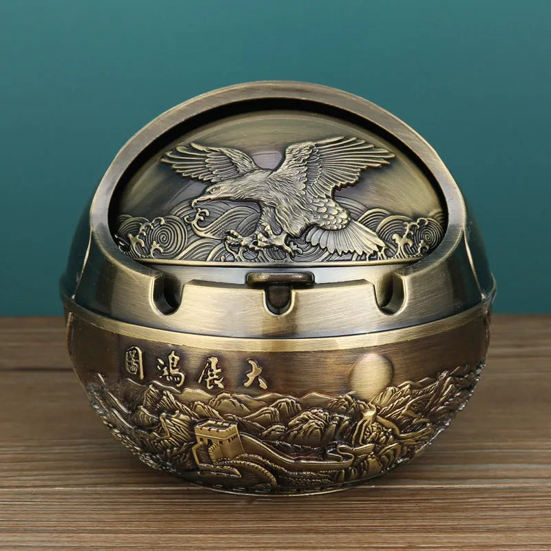 Alloy decorative ashtray in bronze with ornate peacock motif and cigarette extinguishing slot.