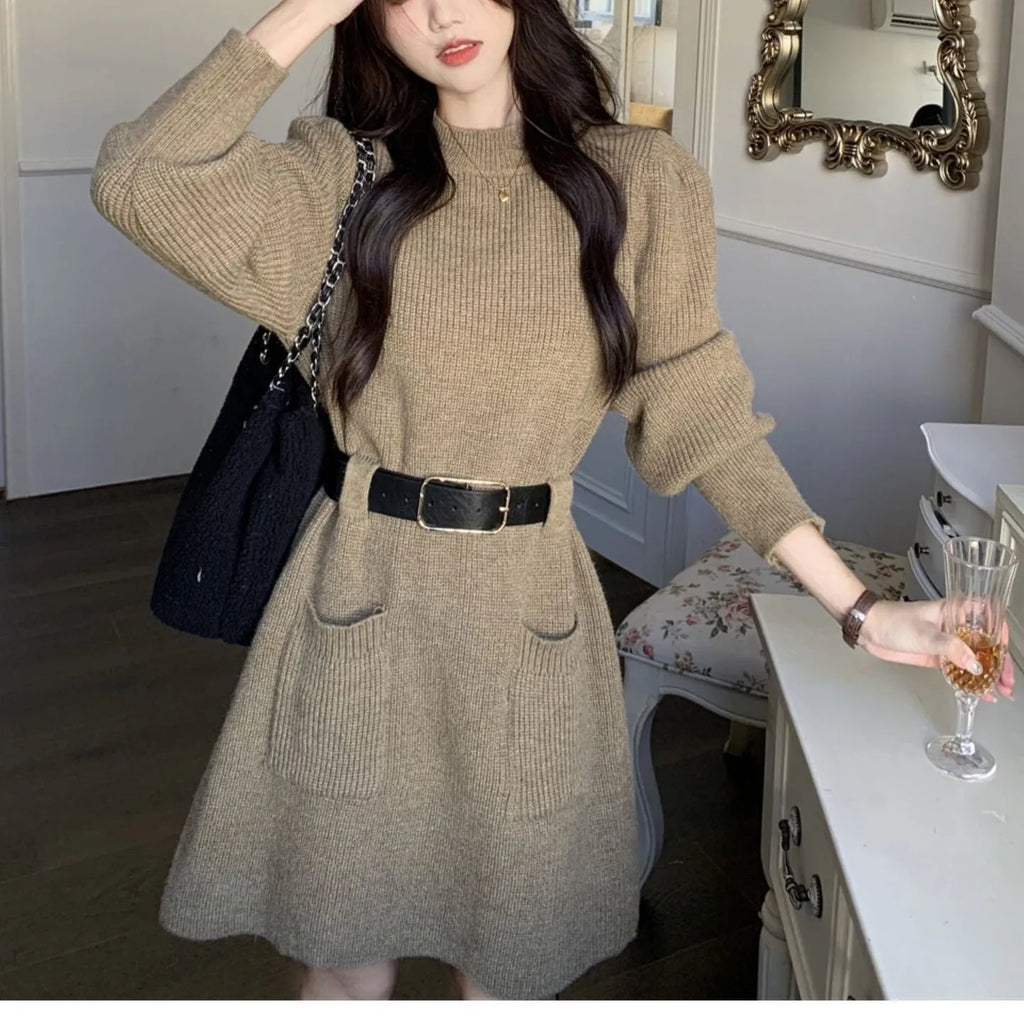 Long sleeve loose knitted dress for women in beige with a black belt, shown on a hanger.