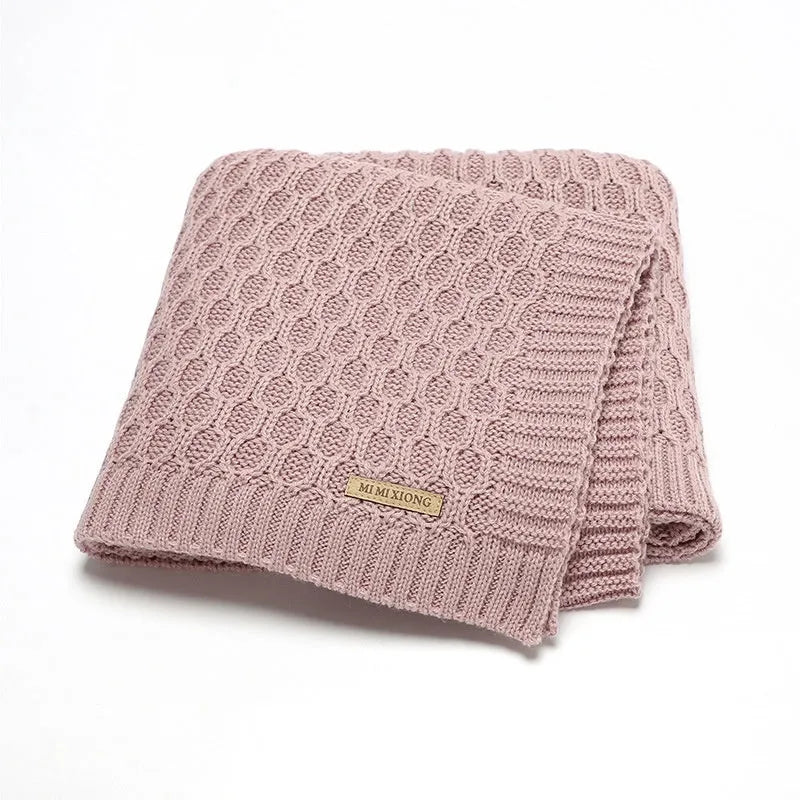 Solid colour infant hug blanket with a three-dimensional lines texture, shown in a soft pink shade.