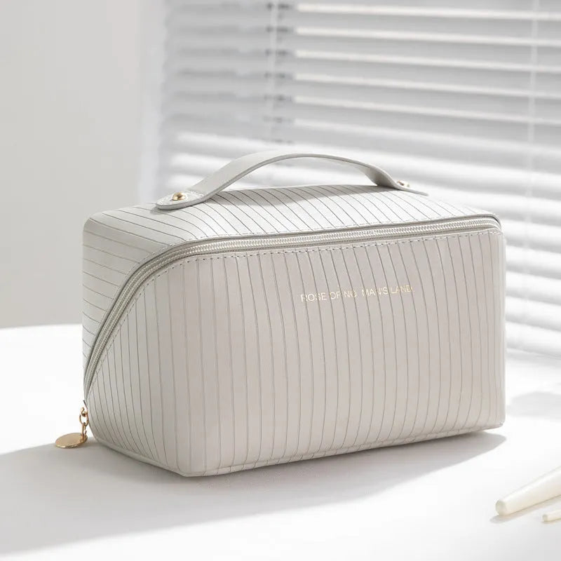 Vertical pattern pillow-shaped cubic makeup bag in PU material, shown in a neutral colour.