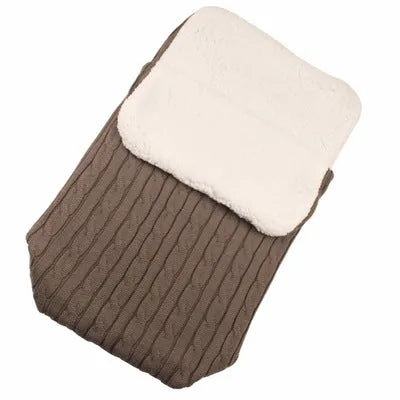 Envelope-style baby stroller sleeping bag in beige colour with thick filling, shown next to a pram.