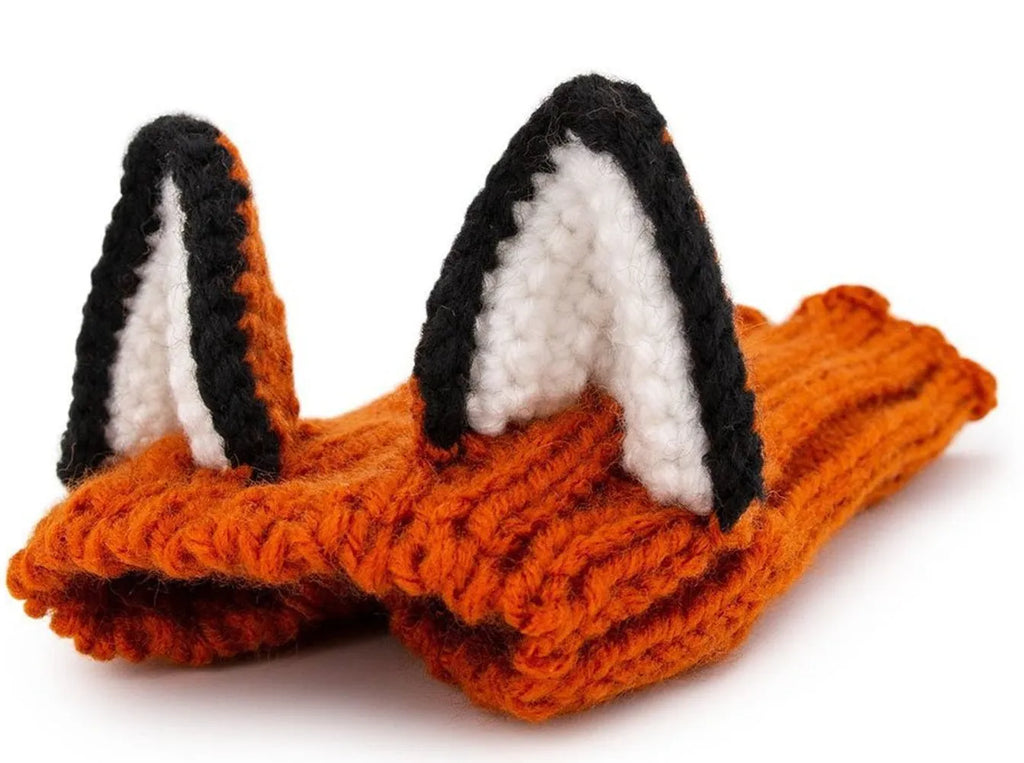Black cow patterned thermal windproof knitted bull dog hat on a small dog standing outdoors in autumn.
