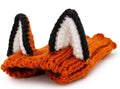Black cow patterned thermal windproof knitted bull dog hat on a small dog standing outdoors in autumn.