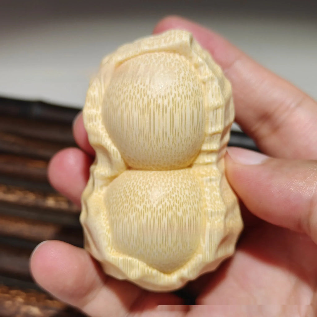 Solid natural bamboo peanut ornament with engraved message on wooden surface