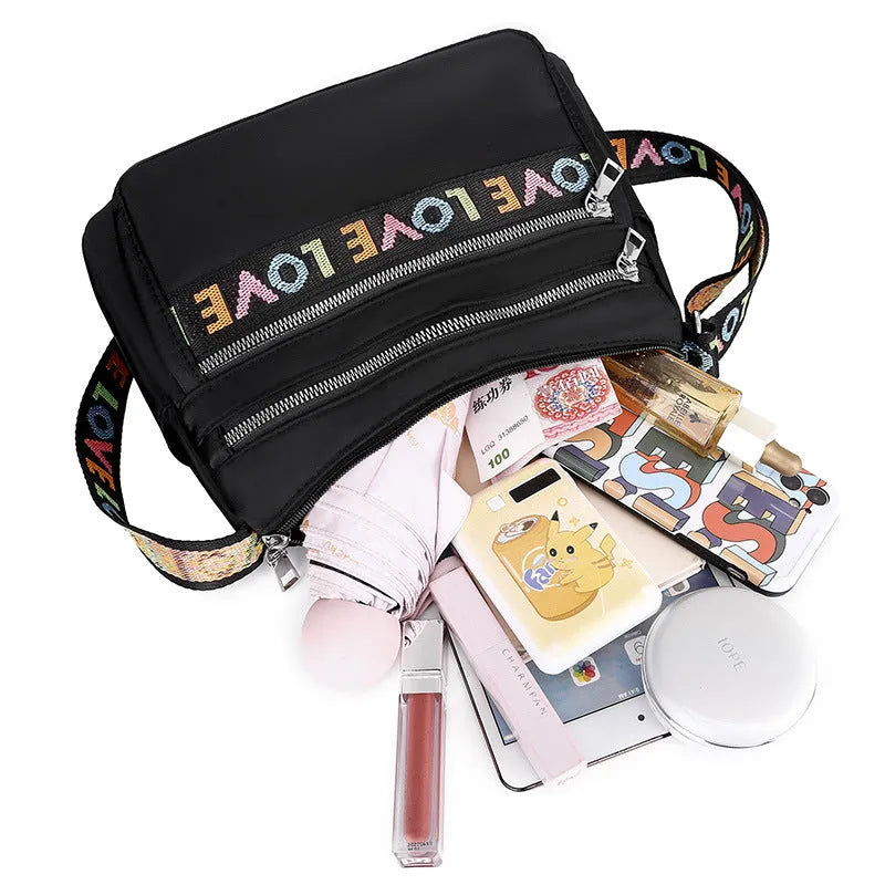 Oxford cloth crossbody shoulder bag in red or black with multi-pocket design, single strap, polyester lining, and letter stitching detail.