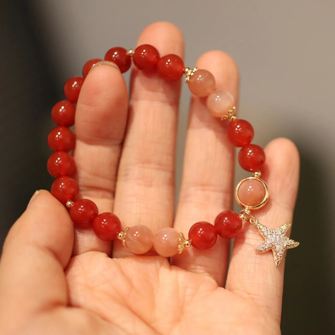 Handmade red agate bracelet with 8mm beads, star and xiangyun patterns, on a wrist.
