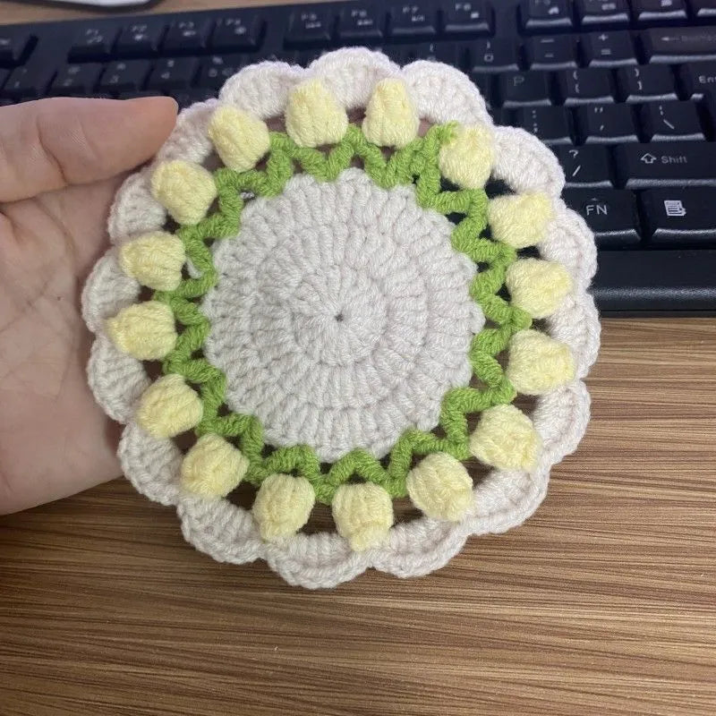Handmade woven floral coaster in cotton and linen on a wooden table