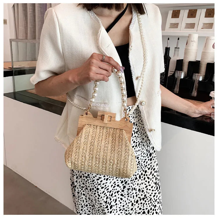 Women's woven straw shoulder bag with pearl chain strap showing internal organisation compartments