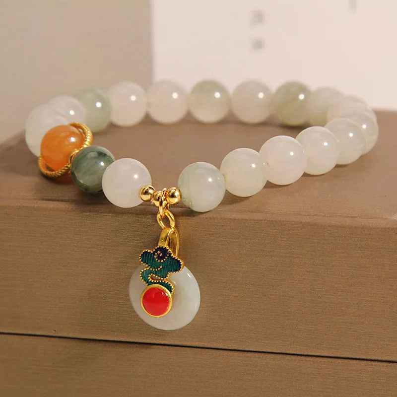 Women's ice jade bracelet with Xiangyun peace buckle and pearl details on a wrist.