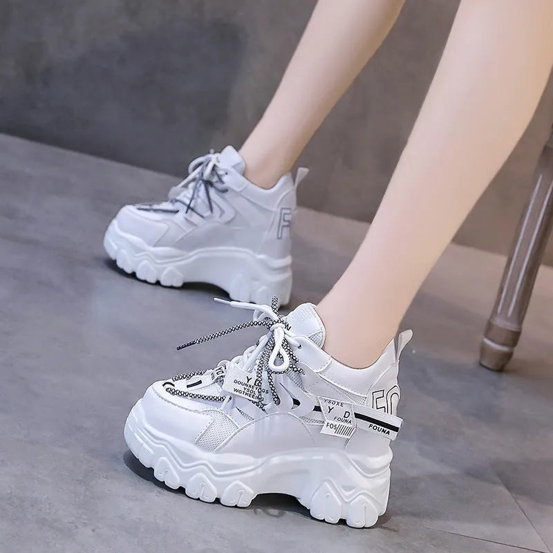 Women's white low-top platform sports shoes with a mesh upper and cross-strap detail.