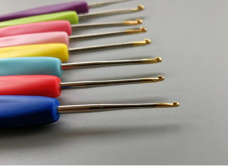 Set of 16 coloured crochet hooks with two handle types laid next to a grey PU fabric storage bag.