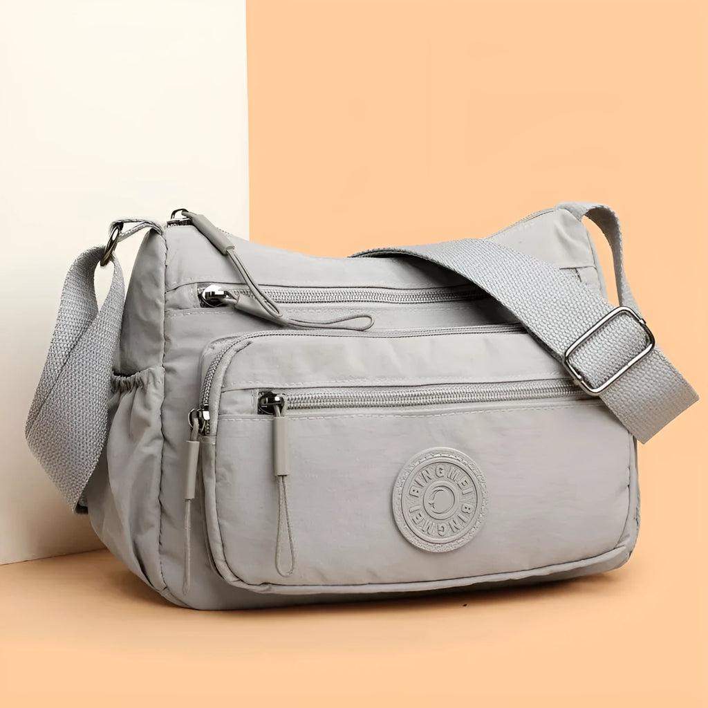 Soft water-repellent nylon crossbody bag with a three-dimensional front pocket and adjustable strap.