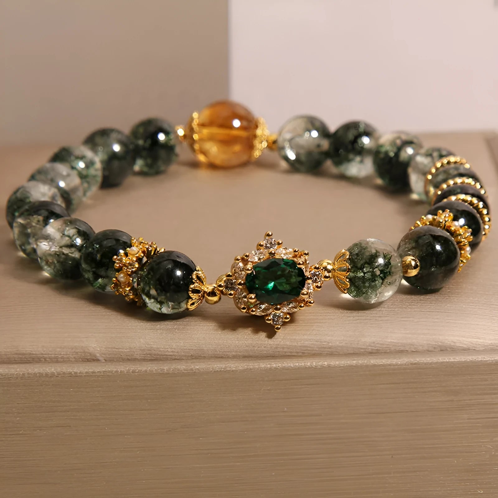 Gold electroplated women's bracelet with a green phantom quartz stone, ruby accents, rhinestones, and pearls.