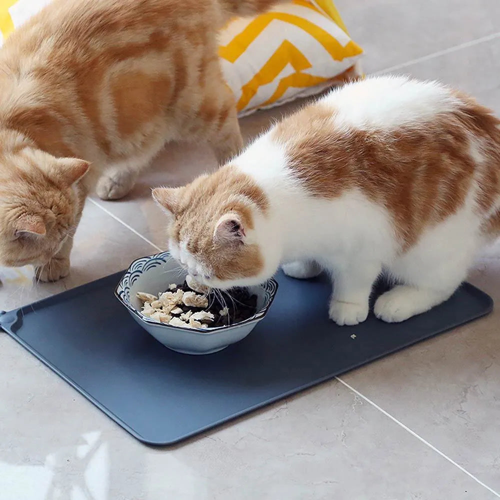 Grey silicone pet food mat with raised edges on a tile floor
