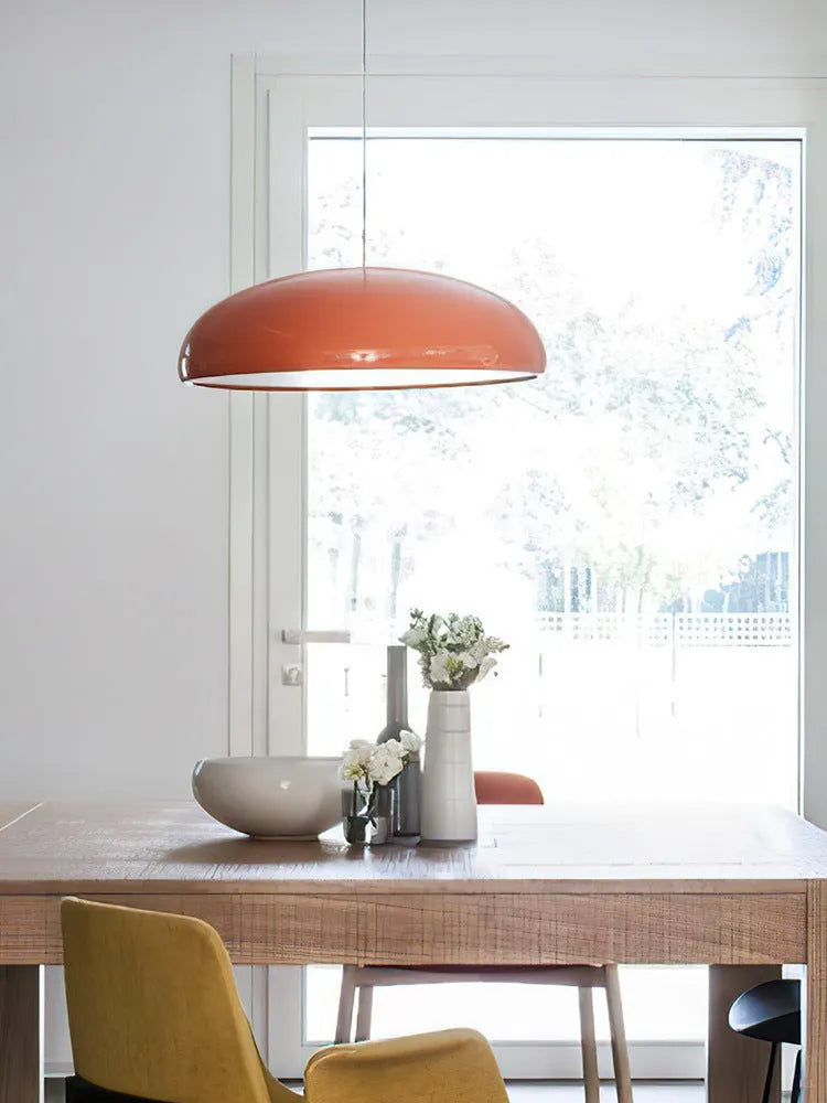 Danish-style iron pendant lamp with adjustable cord above a restaurant table.