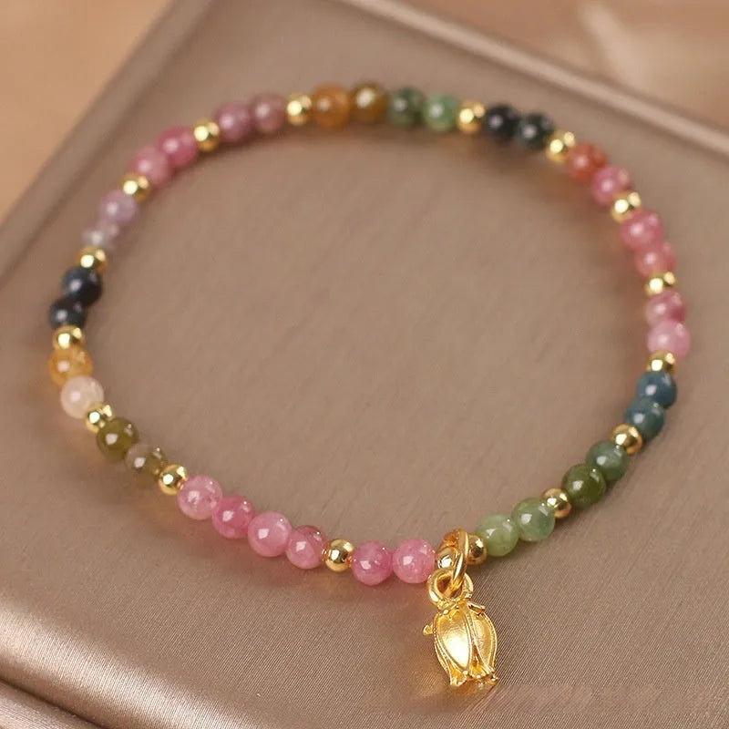 Close-up of a women's beaded anklet with polished tourmaline stones and a detailed metal floral clasp.