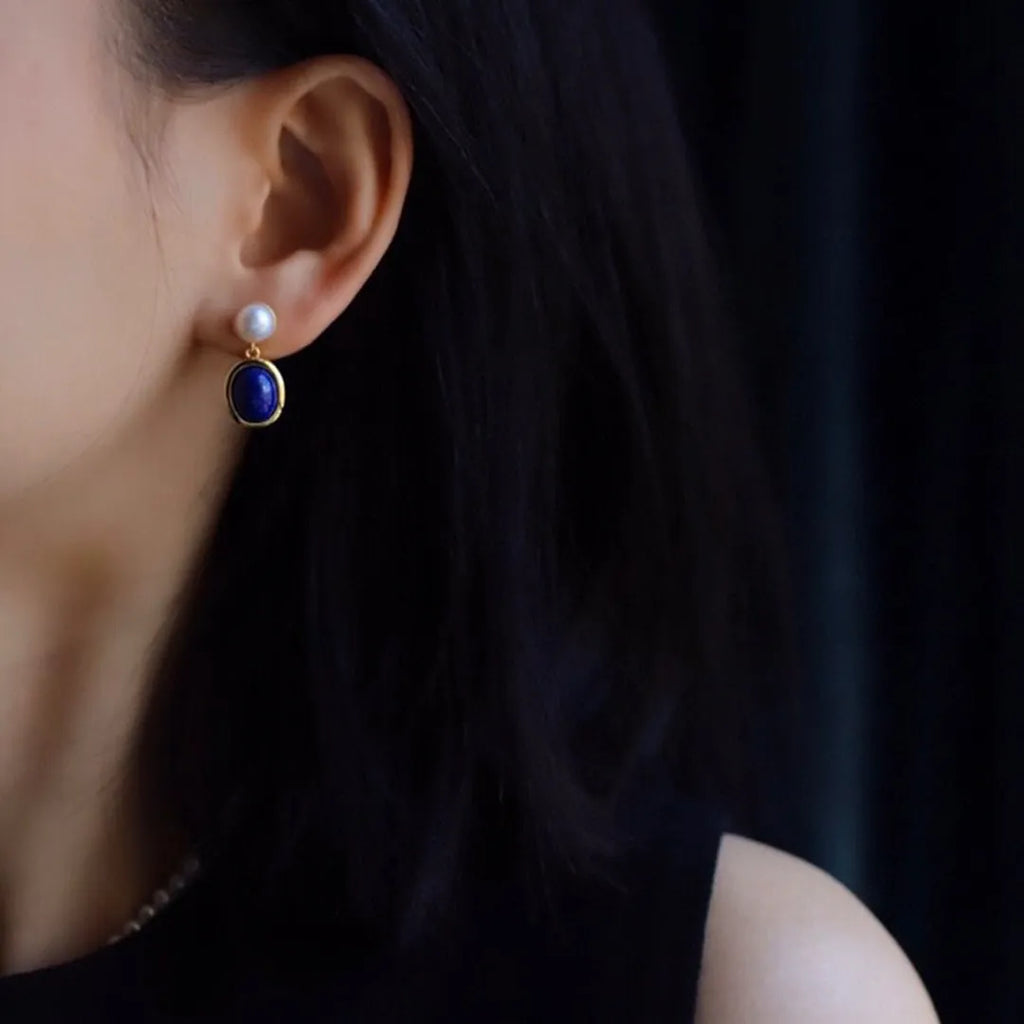 A pair of simple sterling silver earrings with a blue lapis lazuli pearl and auspicious patterns.