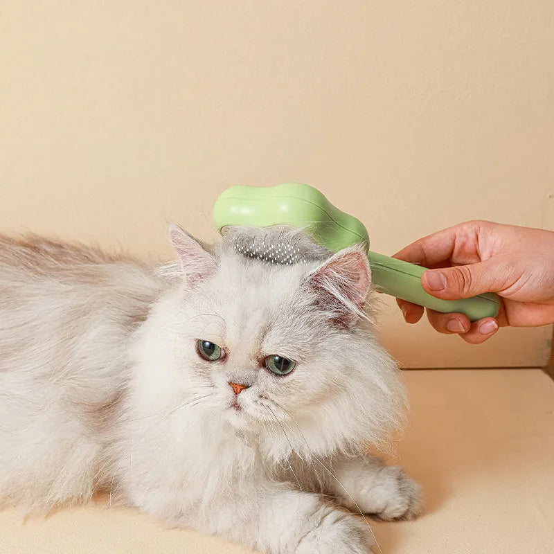 Green self-cleaning stainless steel magic wand cat comb on a white background.