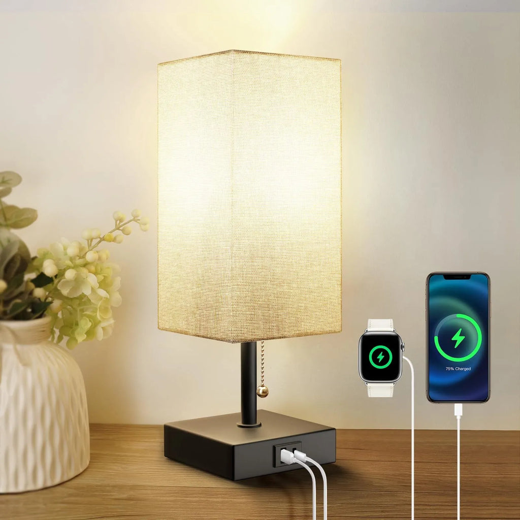 Small bedside table lamp with fabric shade and USB charging ports on a nightstand with pull chain control