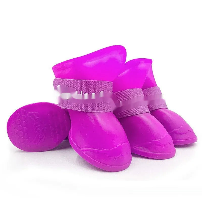 A set of four colourful rubber rain shoes for dogs, showing soft soles and bright pink, blue, orange, and red colours.