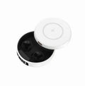 Pair of small black semi-in-ear wireless headphones sitting inside a white charging compartment with lid open.