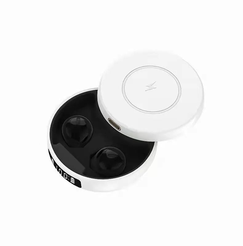 Pair of small black semi-in-ear wireless headphones sitting inside a white charging compartment with lid open.