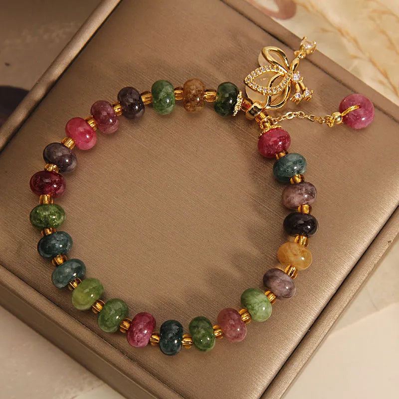 Women's colourful bracelet with alloy butterfly charm and tourmaline beads on wrist.