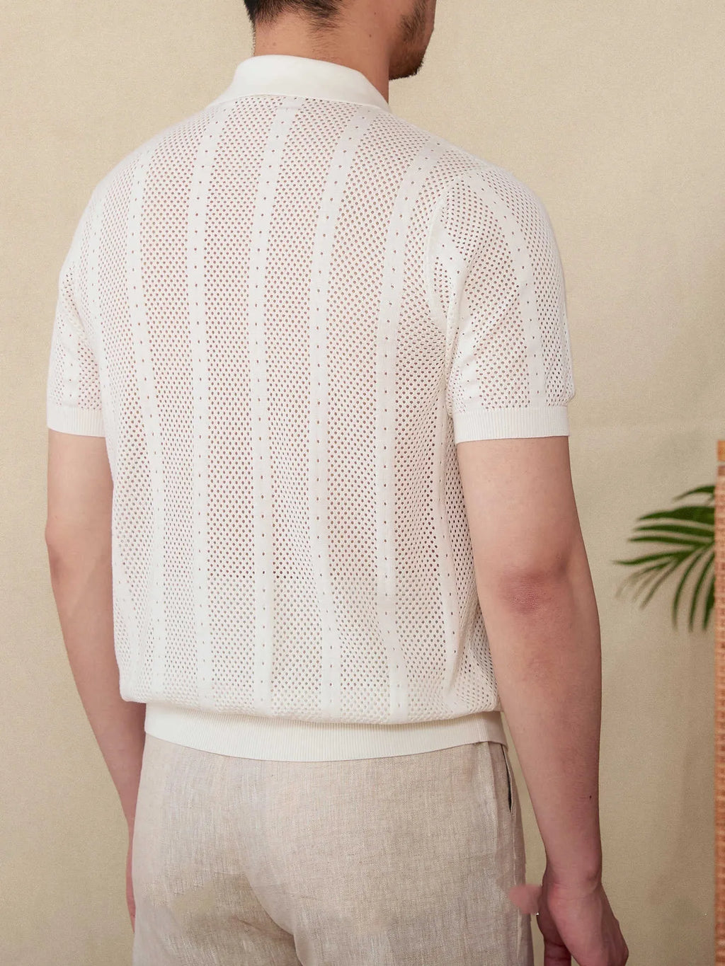 Man wearing a beige striped short sleeve cotton cardigan shirt with a lapel collar.