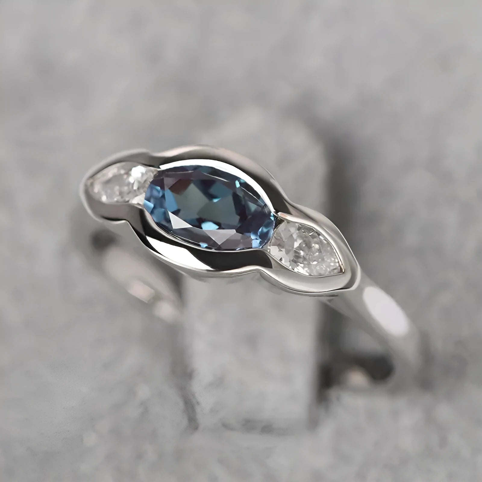 A geometric ellipse-shaped ring with an inlaid zircon, in a white gold colour finish.