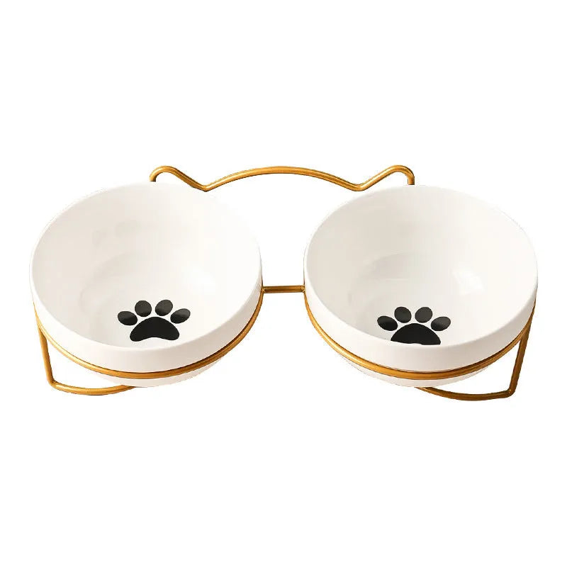 White ceramic cat bowl with cat footprint design on a black iron stand with cat ears.