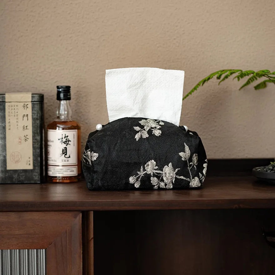 White embroidered plum blossom tissue box cover with fabric texture, shown next to a standard tissue carton for scale.
